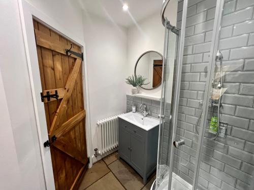 een badkamer met een wastafel en een douche met een spiegel bij Gorgeous 2-Bed Cottage in Penderyn Brecon Beacons in Aberdare