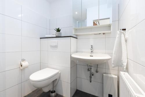 a white bathroom with a toilet and a sink at Blankwasserweg 131 Lensterstrand Oase Bungalow 6 in Lenste