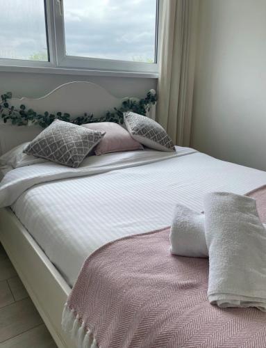 a bedroom with a bed with pillows and a window at Cozy Flat 15 Mins from City Centre with Parking in Cardiff