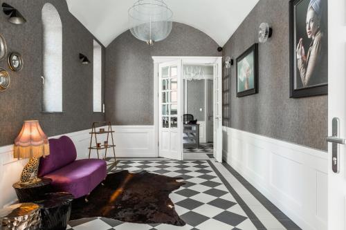 salon z fioletowym krzesłem i podłogą wyłożoną szachownicą w obiekcie Browar Hevelius Apartments w Gdańsku