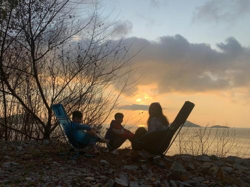 a group of three people sitting in lawn chairs watching the sunset at Uyen's House in Con Dao