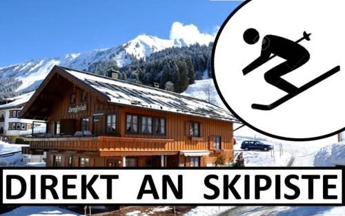 Ein Mann reitet ein Snowboard vor einem Haus in der Unterkunft Das Bergfried - Urlaub zentral und ruhig! in Riezlern