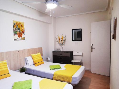 um quarto com 2 camas com lençóis amarelos e brancos em Double cozy room. Ruzafa - perfect place to stay em Valência