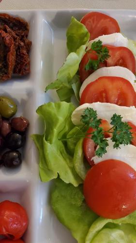 a plate of food with tomatoes lettuce and beans at Landgasthof Steuber - Hotel garni in Bromskirchen