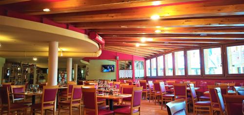 un restaurante con mesas y sillas en una habitación con ventanas en Nevesole Folgarida Resort Aparthotel, en Dimaro