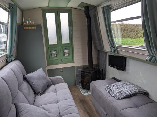 a living room with a couch and a stove at Mini Escape - 2 Berth Narrowboat on the Grand Union, Hertfordshire 