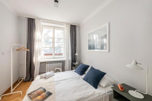 Un dormitorio con una cama con almohadas azules y una ventana en ShortStayPoland Piwna (B79), en Varsovia