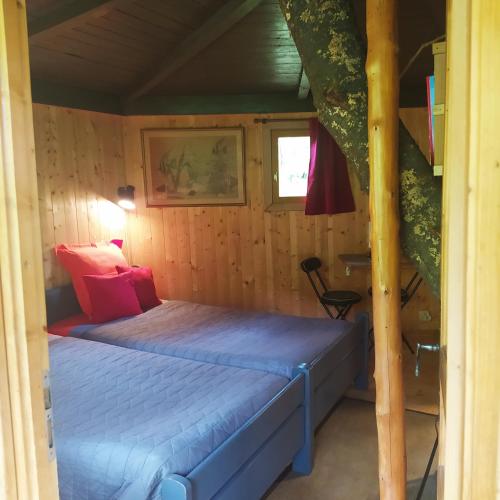 um pequeno quarto com uma cama num camarote em CABANE CERISE DANS L'ARBRE Etapeboisee em Fumay