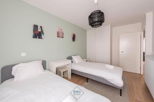 deux lits dans une petite pièce avec des draps blancs dans l'établissement Ariane place Disneyland BMYGUEST, à Chessy