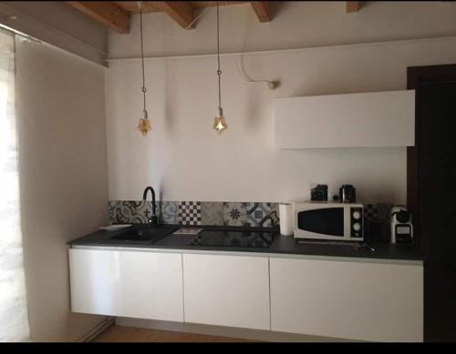 a kitchen with white cabinets and a microwave at Kosikome in Ferrara