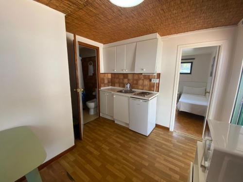 una cocina con armarios blancos y una cama en una habitación en Camping Giralda, en Huelva