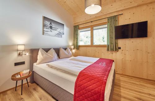 a bedroom with a large bed with a red blanket at AlpenParks Chalet & Apartment Steve Lodge Viehhofen in Viehhofen