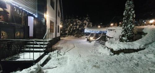 a snow covered street at night with a building at L - Hutir in Mykulychyn