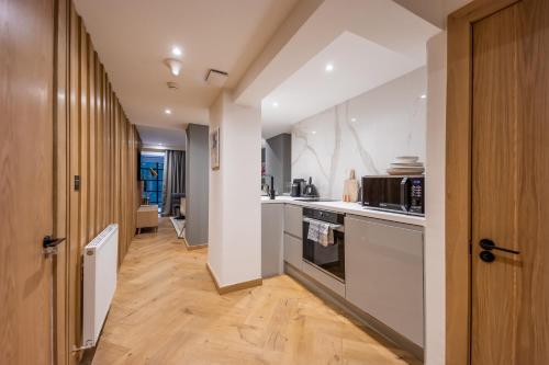 a kitchen with white appliances and a wooden floor at No1 Apartments Edinburgh - New Town in Edinburgh