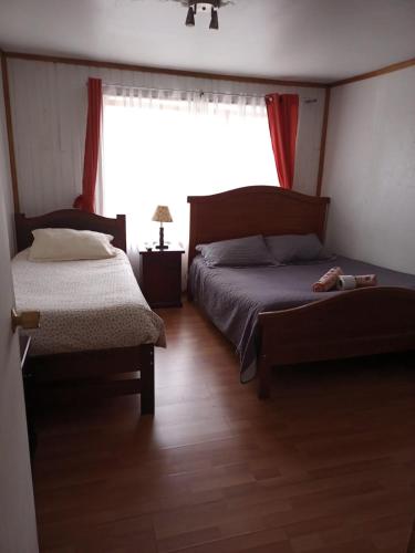 a bedroom with two beds and a window at Hostal Valentino in Villarrica