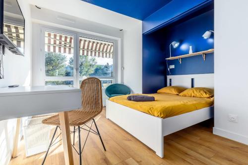 a bedroom with blue walls and a bed with a desk at Le Bleu Royal Appart Hotel - 5 Chambres in Évry-les-Châteaux