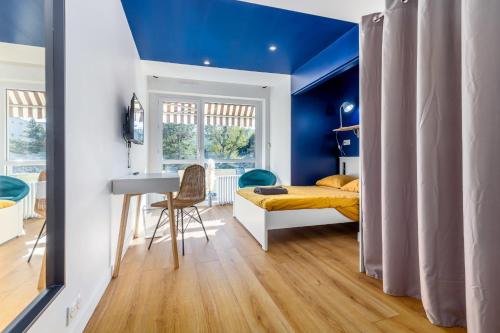 a bedroom with blue walls and a bed and a desk at Le Bleu Royal Appart Hotel - 5 Chambres in Évry-les-Châteaux