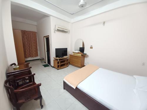 a bedroom with a bed and a chair and a television at Nhật An Hotel in Ho Chi Minh City