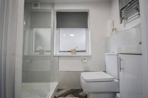 a white bathroom with a toilet and a window at Self contained studio in Chorley by Lancashire Holiday Lets in Chorley