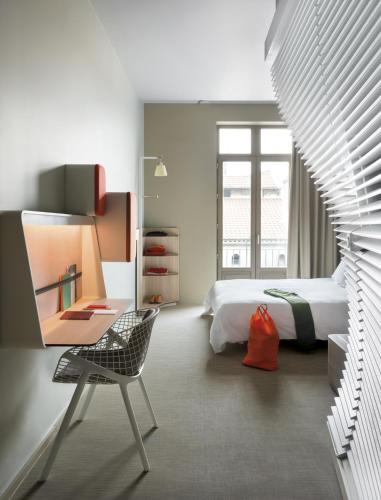 a bedroom with a bed and a desk and a chair at OKKO Hotels Lyon Centre in Lyon