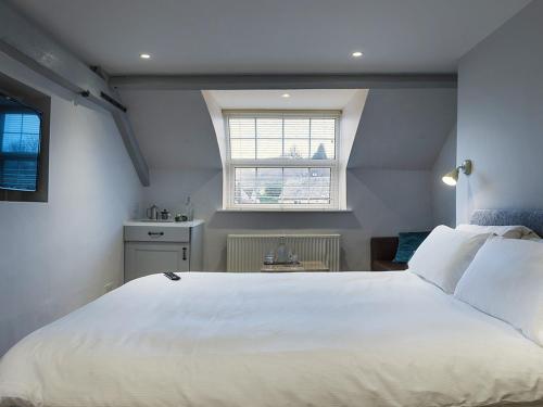 a bedroom with a large white bed and a window at Wild Garlic Rooms in Nailsworth