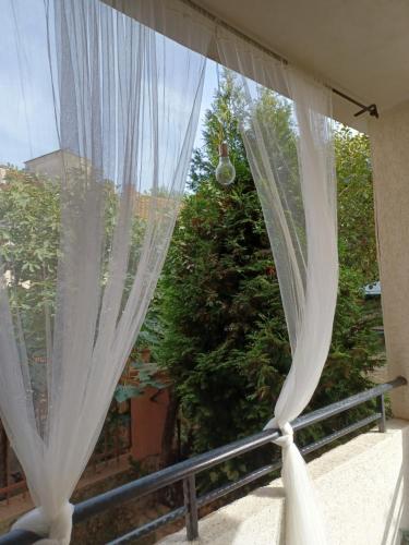 a window with white curtains and a tree at Tara Deluxe Apartment in Varna City
