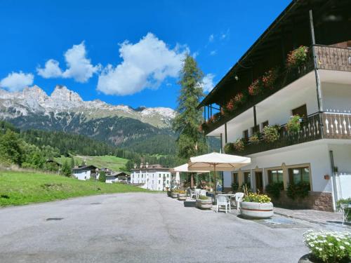 a building with a table and chairs and an umbrella at Albergo Scoiattolo in Falcade