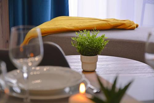 a table with a wine glass and a plant on it at Sun Towers - Apartamenty Bryza - Apartamenty z parkingiem in Świnoujście