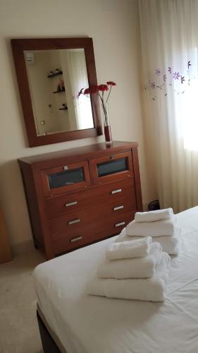 ein Schlafzimmer mit einer Kommode mit einem Spiegel und Handtüchern auf einem Bett in der Unterkunft chalet relax luxury in Navas del Rey