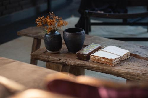 una mesa de madera con dos jarrones y libros. en The Bohemian Bali en Canggu