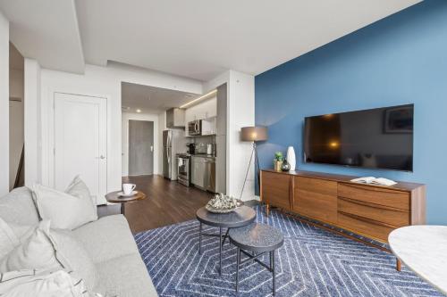 a living room with a couch and a flat screen tv at Placemakr Marymount Ballston in Arlington