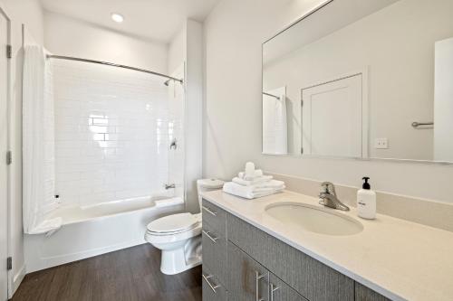 a bathroom with a sink and a toilet and a mirror at Placemakr Marymount Ballston in Arlington