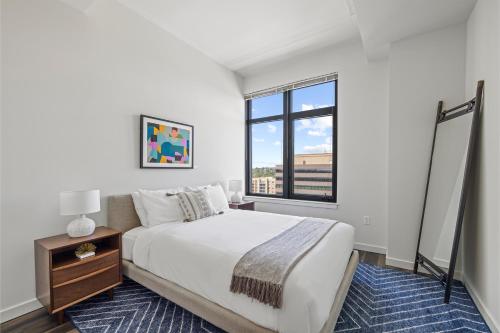 a white bedroom with a large bed and a window at Placemakr Marymount Ballston in Arlington