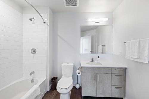 a white bathroom with a toilet and a sink at Placemakr Marymount Ballston in Arlington