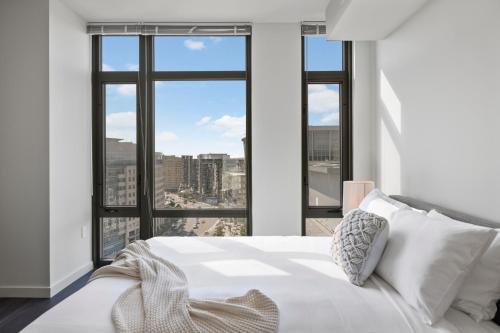 a bedroom with a white bed and large windows at Placemakr Marymount Ballston in Arlington