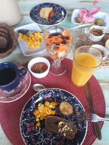 a table with plates of food and a glass of orange juice at Pousada Vila Cacau in Serra Grande