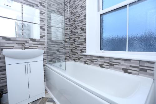 a bathroom with a white sink and a window at London Town Apartment- Lewisham in London