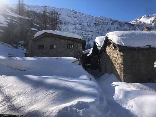 a house covered in snow next to a building at Chalet 1728 - La Reculaz - 2 minutes from Val D'isere by free shuttle bus in Tignes