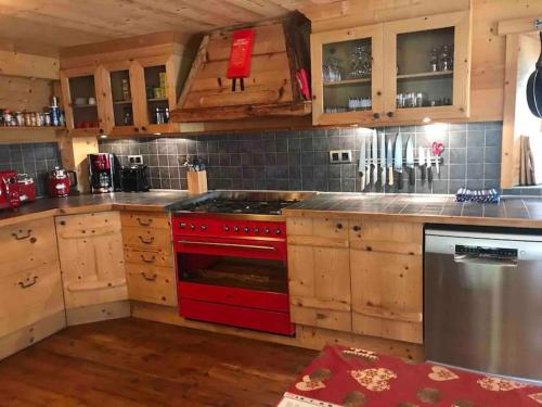 a kitchen with a red stove and wooden cabinets at Chalet 1728 - La Reculaz - 2 minutes from Val D'isere by free shuttle bus in Tignes