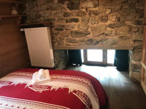 a bed in a room with a stone wall at Chalet 1728 - La Reculaz - 2 minutes from Val D'isere by free shuttle bus in Tignes