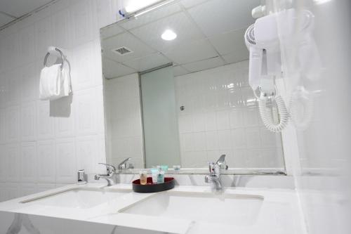 La salle de bains blanche est pourvue d'un lavabo et d'un miroir. dans l'établissement Nine Hotel, à Dubaï