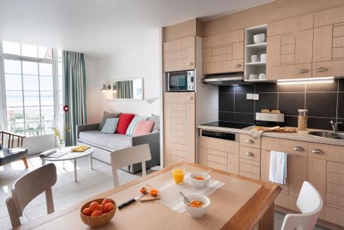 a kitchen and a living room with a table and chairs at Pierre & Vacances Premium Résidence de la Plage in Le Crotoy