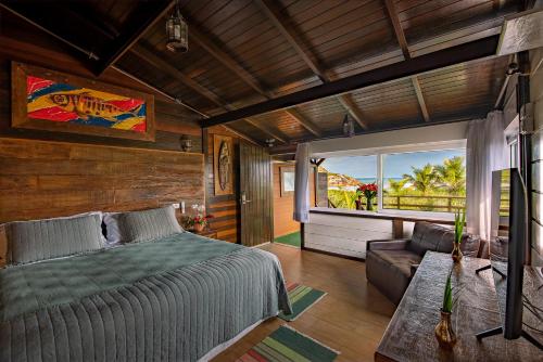 a bedroom with a bed and a couch and a window at Grajagan Surf Resort in Ilha do Mel