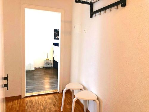 a hallway with two white stools and a mirror at INN JOY Apartments - Rorschach mit Panoramasicht in Rorschach