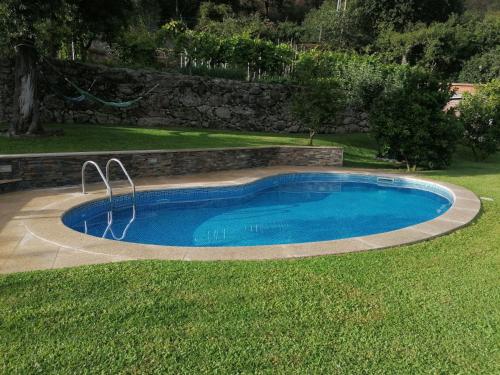 a swimming pool in a yard with a grass field at Kombi House in Terras de Bouro