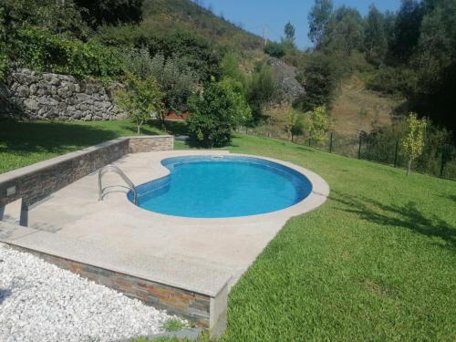 a swimming pool in the middle of a grass field at Kombi House in Terras de Bouro