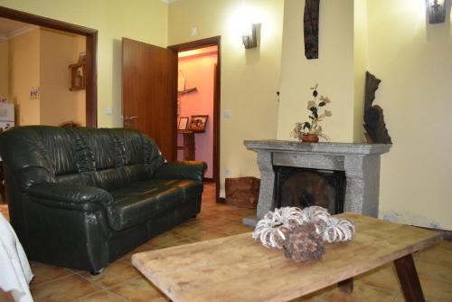 a living room with a leather couch and a fireplace at Casa na Serra da Estrela in Melo