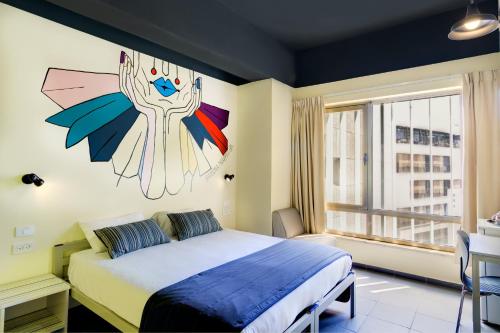 een slaapkamer met een bed met een schilderij aan de muur bij Abraham Tel Aviv in Tel Aviv