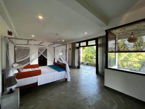 a bedroom with a bed and a large window at My Home Villa in Hikkaduwa