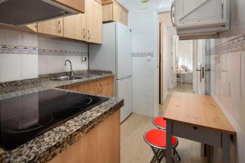 a kitchen with a sink and a counter with two red chairs at Garcia Briz by Bossh! Apartments in Málaga